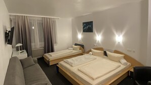 A hotel room with two single beds, a sofa, a chair, a desk, and a window with curtains. - Hotel Luise (Essen)