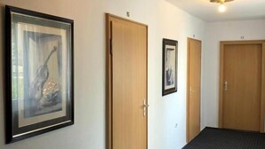 A hallway with three wooden doors, numbered 15, 17, and another door with a number. There are framed pictures on the walls. - Hotel Luise (Essen)