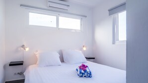 Ein Hotelzimmer mit einem Bett, zwei Nachttischlampen, einem Fenster und einer Klimaanlage.