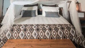 Una cama con dosel, un edredón estampado y un cabecero de madera.