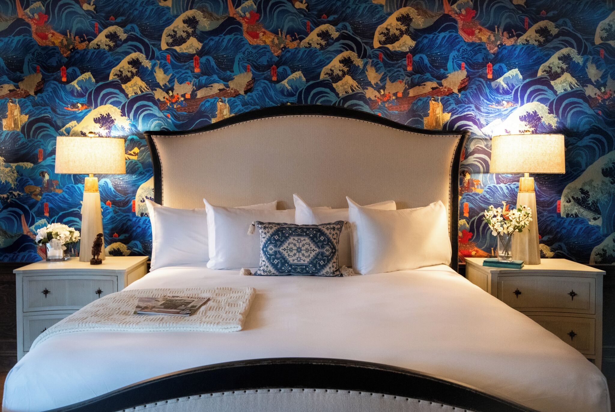 A bed with white linens, a decorative pillow, and two bedside tables with lamps.