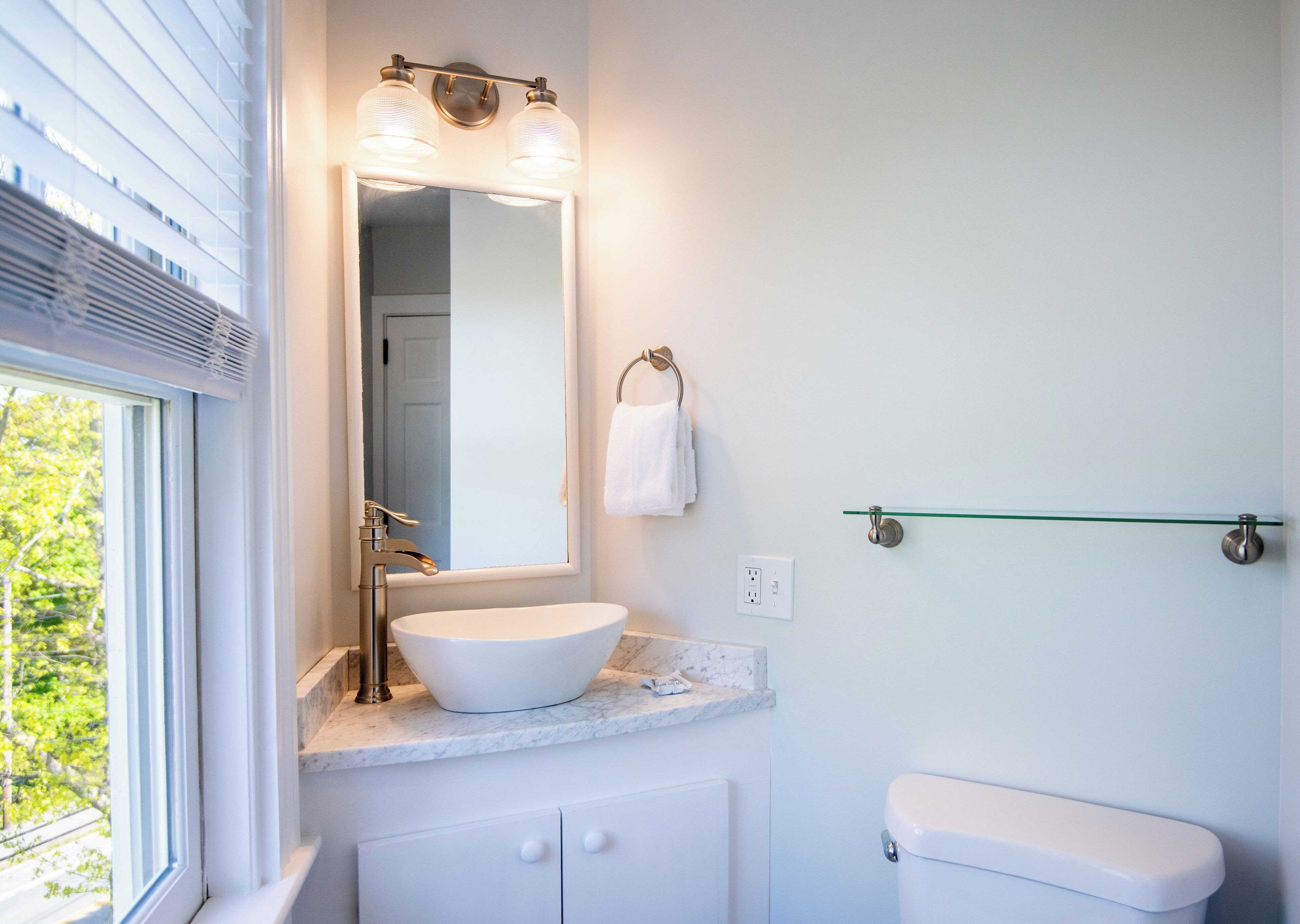 A bathroom with a white sink, a mirror, and a toilet.
