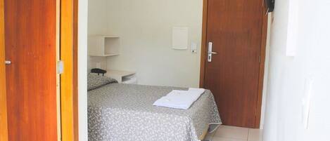 Une chambre à coucher comprenant un lit, un bureau, une chaise, une armoire et une porte.