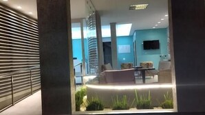 Vestíbulo moderno de hotel con mostrador de recepción, zona de estar y una pantalla de televisión.