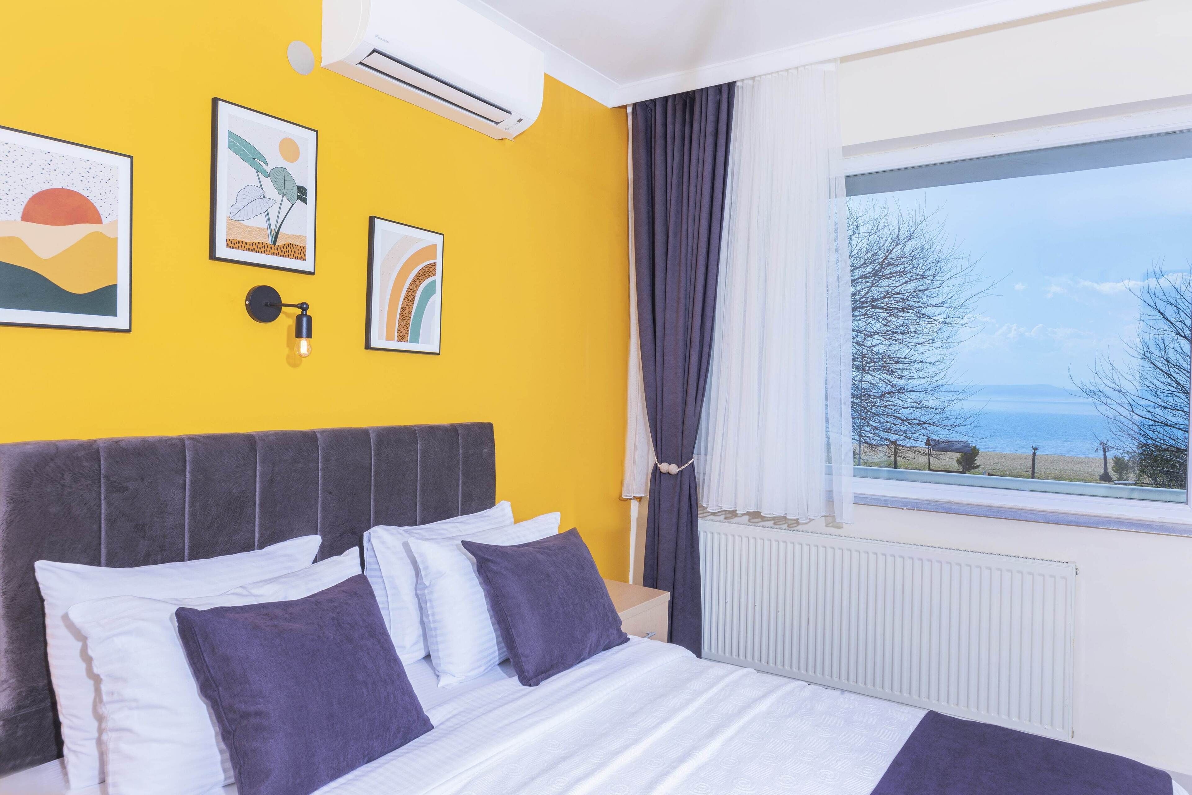 A bedroom with a bed, a window with a view, and wall art.