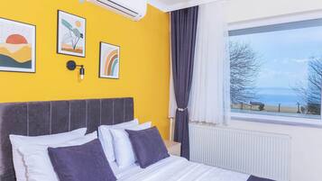 A bedroom with a bed, a window with a view, and wall art.