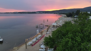 Un hotel frente a la playa con sillones de sol, alfombra roja y vistas al mar y al atardecer.