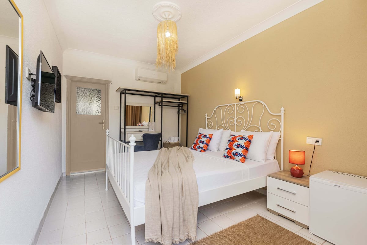 A bedroom with a bed, bedside table, lamp, and a wardrobe.