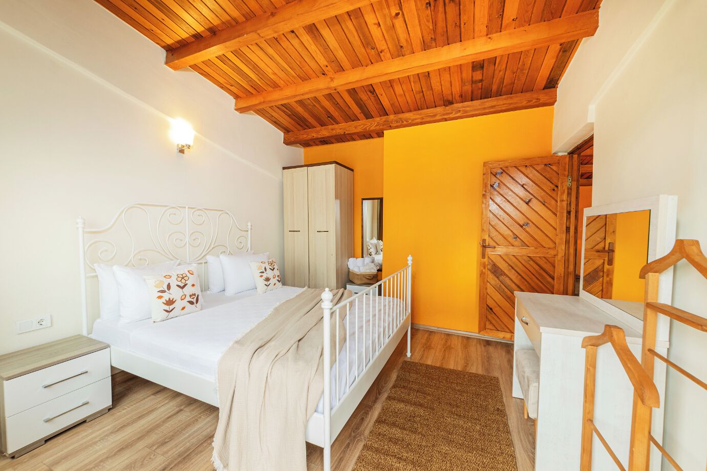 A bedroom with a bed, nightstand, wardrobe, and a wooden door.