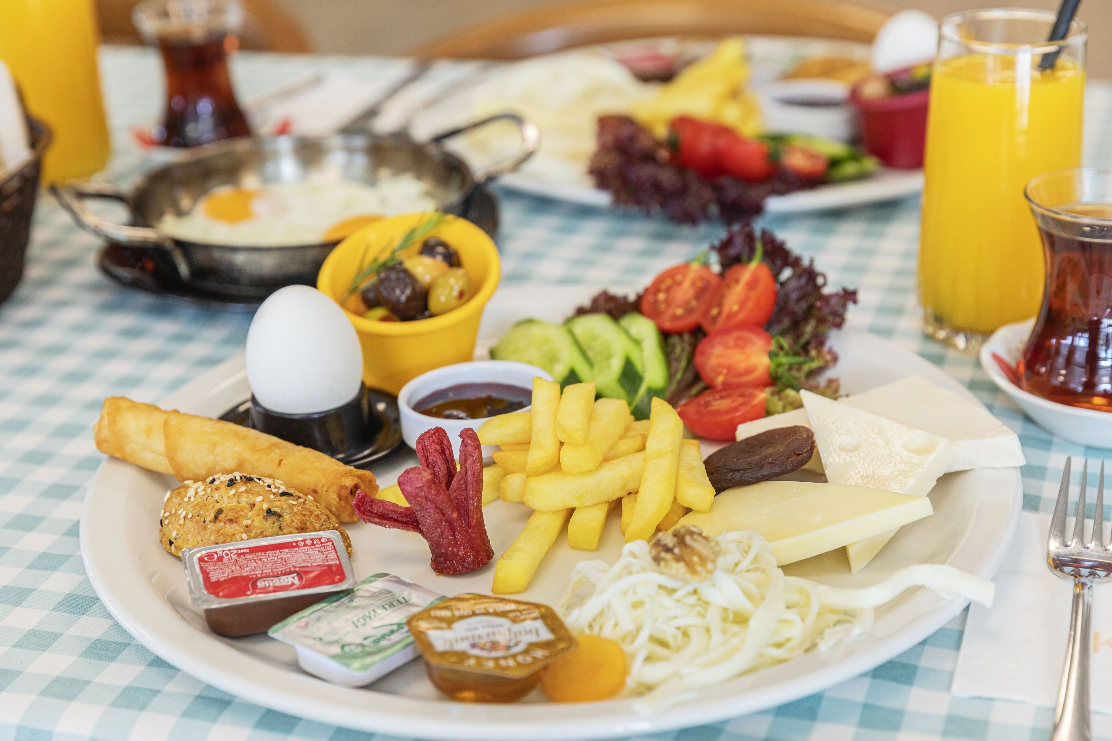 A plate of food with various items including eggs, fries, and vegetables.