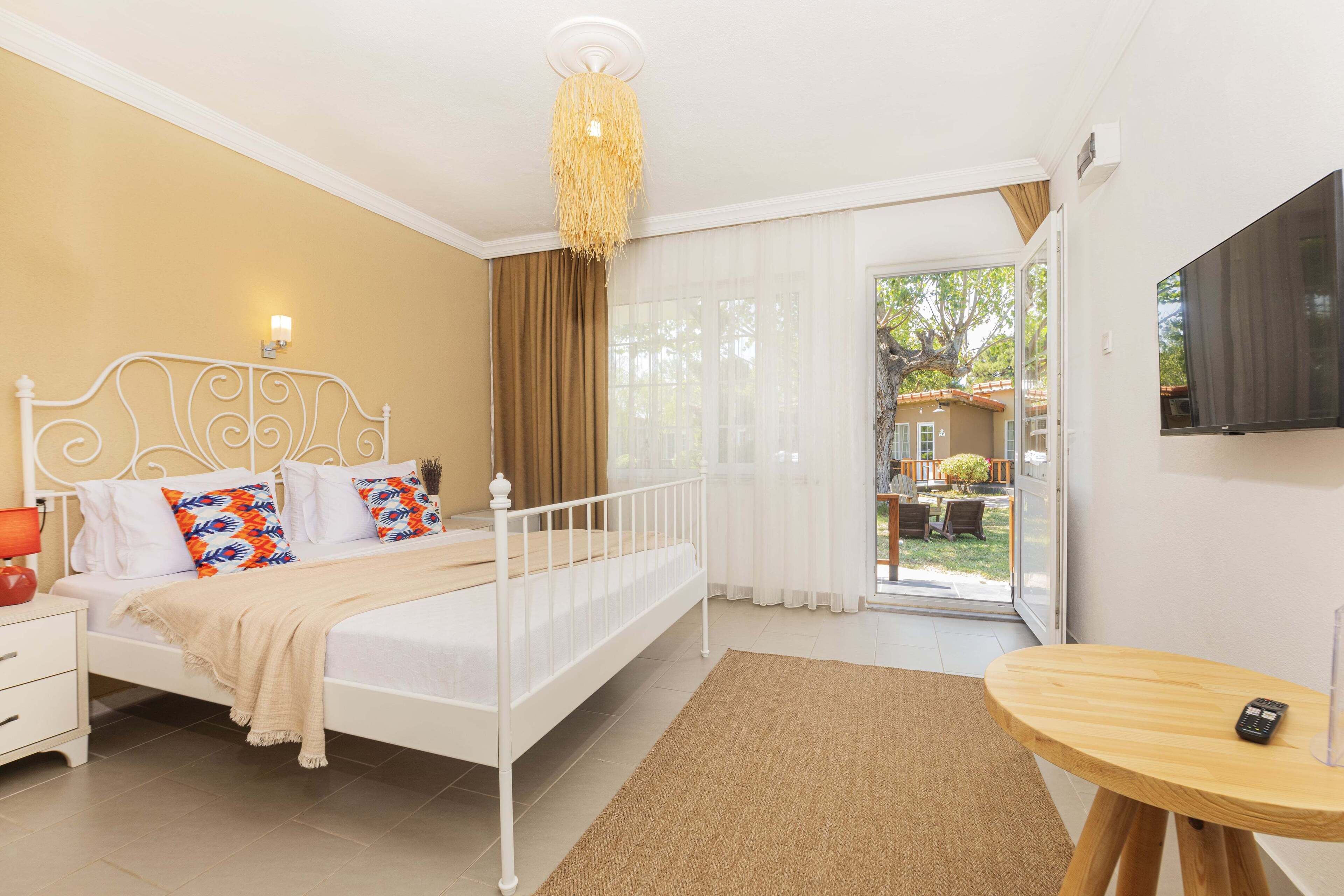 A bedroom with a bed, bedside table, and a TV on the wall.