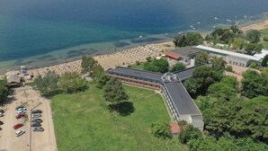 Vista aérea de una propiedad costera con playa, estacionamiento y un edificio de techo inclinado.