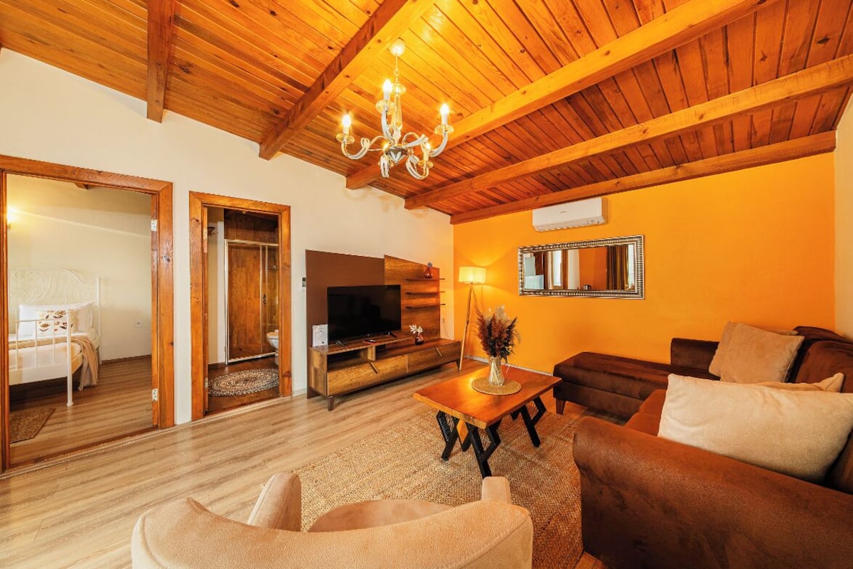 A cozy living room with a wooden ceiling, a TV, a sofa, and a coffee table.