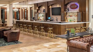A bar area with a long counter, stools, and a TV screen. - Four Points by Sheraton Santa Cruz Scotts Valley (Scotts Valley)