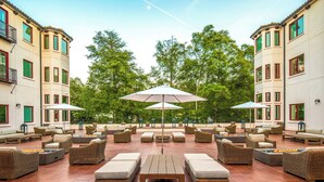 An outdoor lounge area with wicker furniture, large umbrellas, and a tiled floor. - Four Points by Sheraton Santa Cruz Scotts Valley (Scotts Valley)