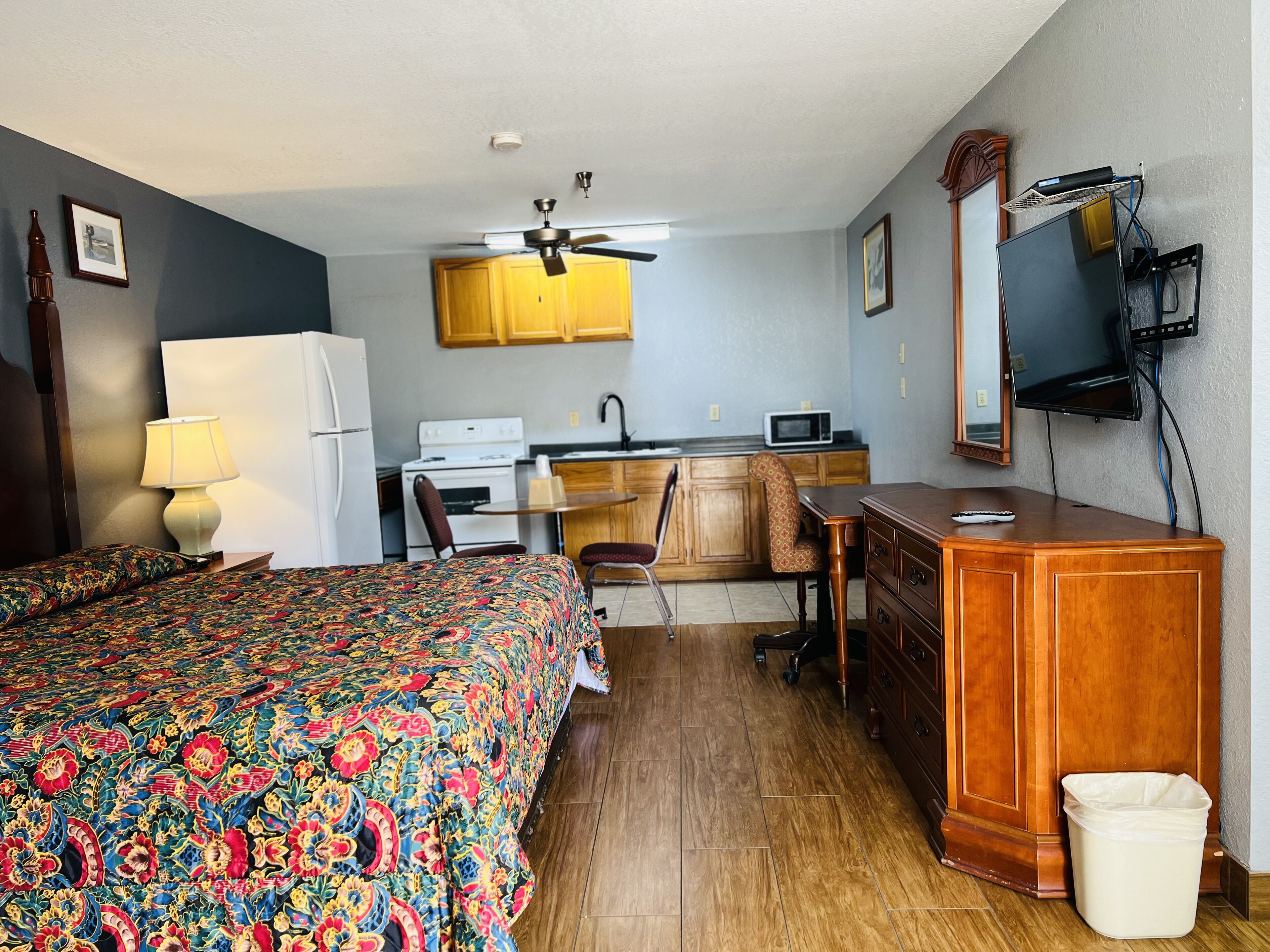 Une chambre d’hôtel équipée d’un lit, d’un bureau, d’une chaise, d’un four à micro-ondes, d’un réfrigérateur, d’un ventilateur de plafond et d’une télévision.