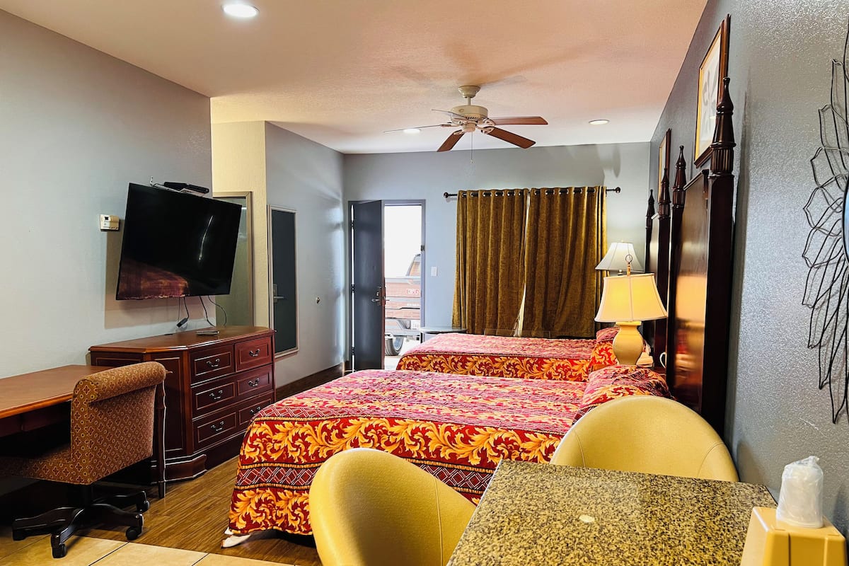 A hotel room with a bed, a desk, a chair, a television, and a ceiling fan.