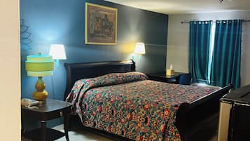 A hotel room with a bed, two bedside tables, a desk with a lamp, a wall-mounted picture, and a ceiling fan.