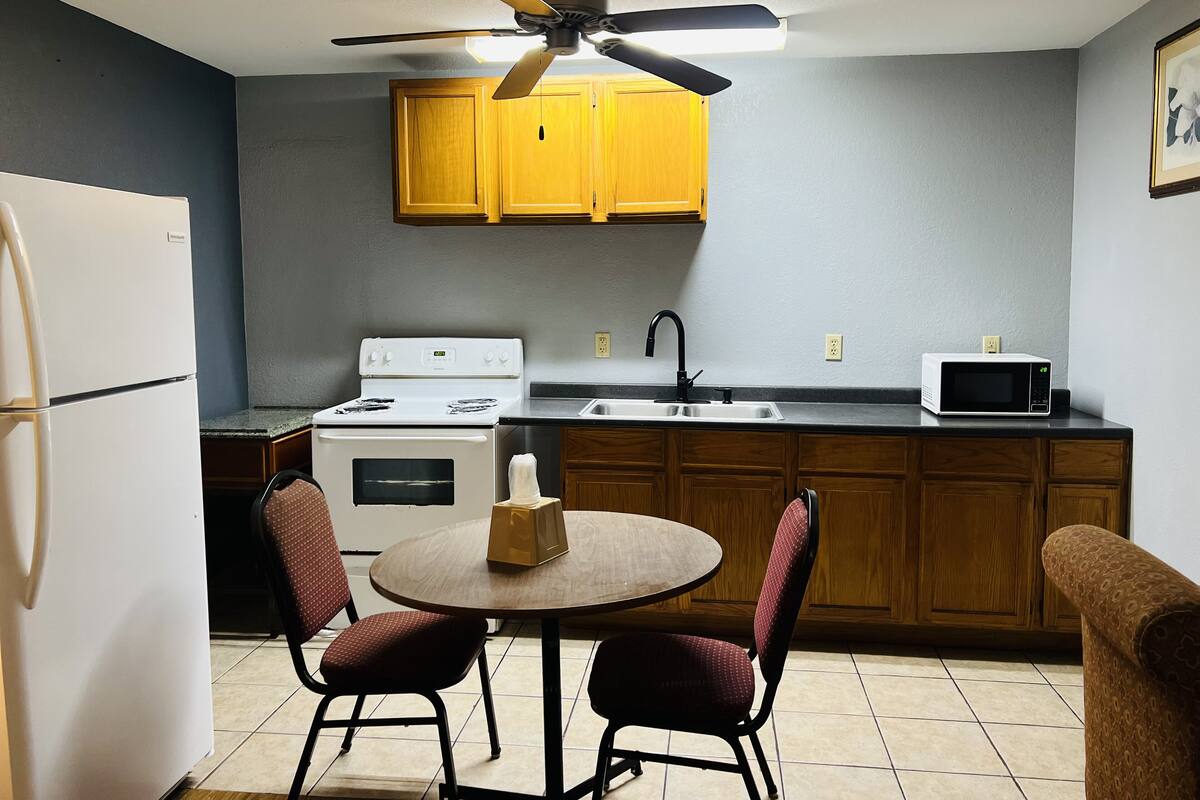 A compact kitchen with a refrigerator, stove, microwave, and wooden cabinets.