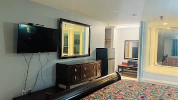 Une chambre d’hôtel avec un lit, une commode, une télévision et un miroir.