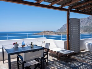 A terrace with a table, chairs, and a view of the sea and mountains. - Blue Dawn Kalymnos (Kalymnos)