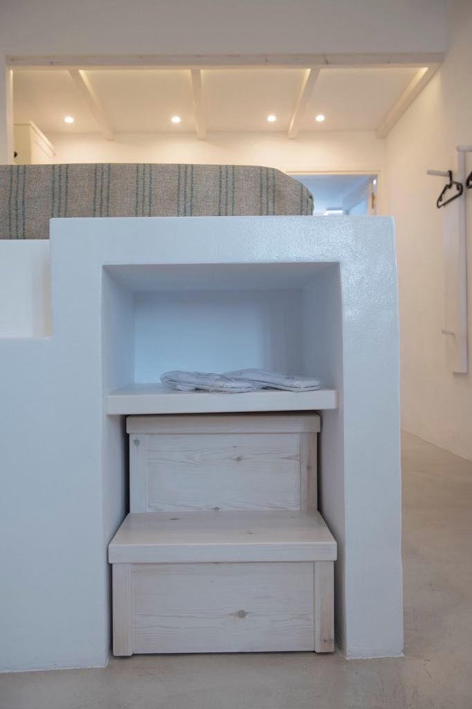 Habitación compacta con cama integrada, un estante pequeño y un cajón para guardar objetos.