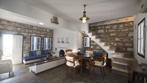 Un comedor acogedor con pared de piedra, escalera de madera y vista al mar.