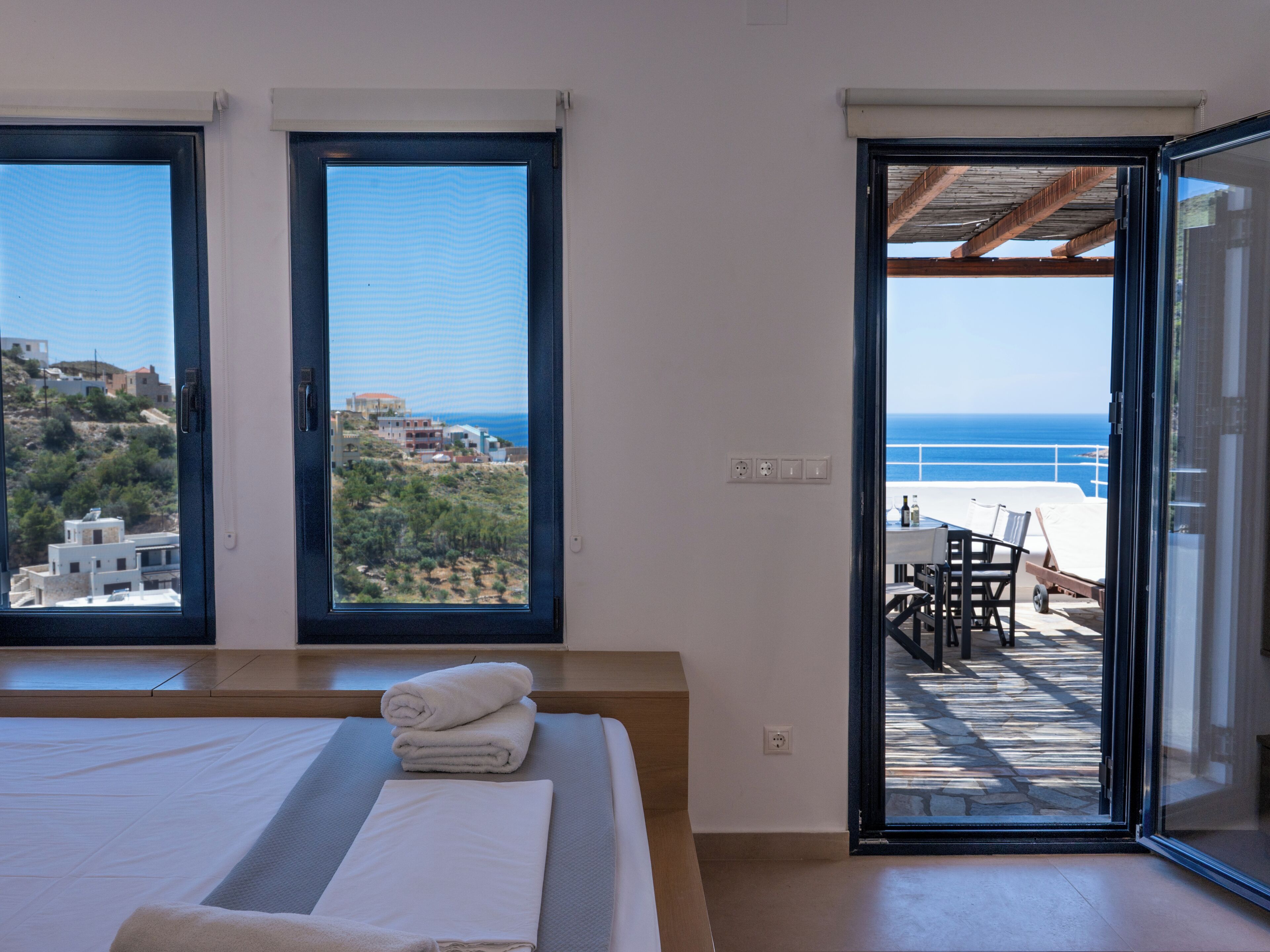 Una camera da letto con un letto grande, due finestre e un balcone con vista sul mare.