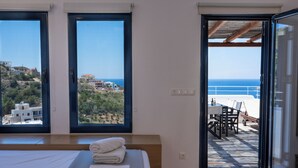 Un dormitorio con una cama grande, dos ventanas y un balcón con vista al mar.