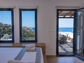 Un dormitorio con una cama grande, dos ventanas y un balcón con vista al mar.