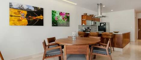 Una cocina moderna con una isla central, sillas de madera y una mesa de comedor.