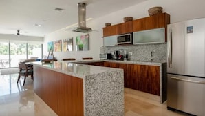 Een moderne keuken met granieten aanrechtbladen, roestvrijstalen apparatuur en houten kastjes.