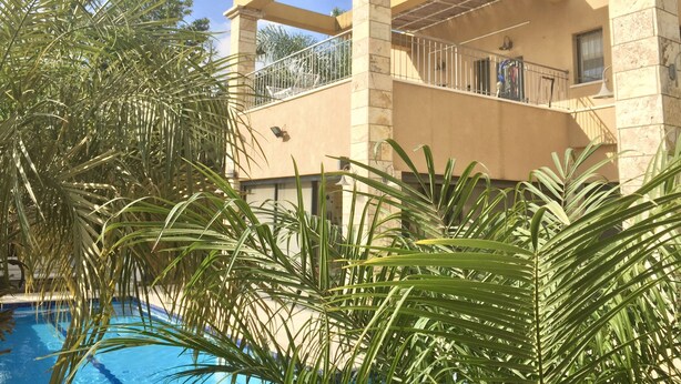 A building with a pool surrounded by palm trees.