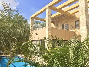 A building with a pool surrounded by palm trees.