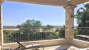 A balcony with a view of a distant landscape, a baby stroller, and a hot tub.