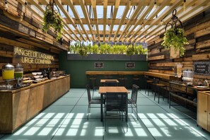 Un café con un interior rústico de madera, una pared verde y diversas opciones de asientos.