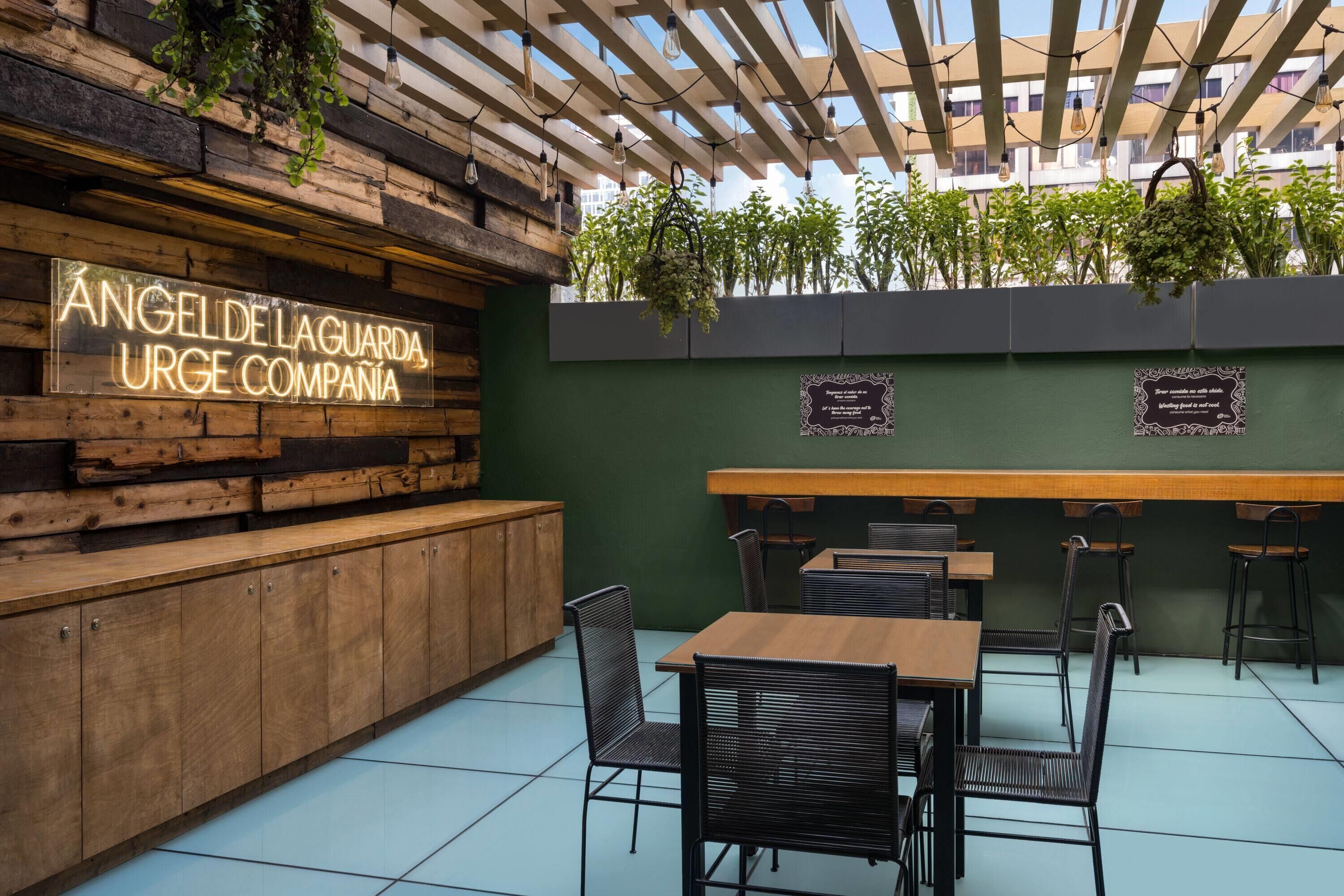 A restaurant with a wooden wall, a neon sign, and outdoor seating.
