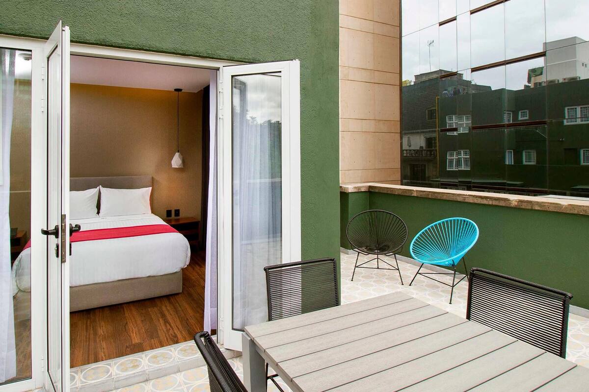 A hotel room with a bed, a table, and two chairs.