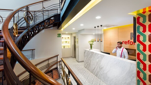 A hotel reception area with a marble counter, a spiral staircase, and a modern design. - Hotel MX mas reforma CDMX, Trademark Collection by Wyndham (Mexico City)
