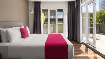 Una habitación de hotel con una cama grande, un balcón con vistas y un ventanal corredero.