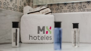 Una bolsa de tela blanca con el logotipo "M&N hoteles" y una botella azul sobre una encimera.