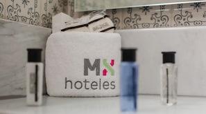 A white towel bag with the logo "M&N hoteles" and a blue bottle on a counter. - Hotel MX mas reforma CDMX, Trademark Collection by Wyndham (Mexico City)