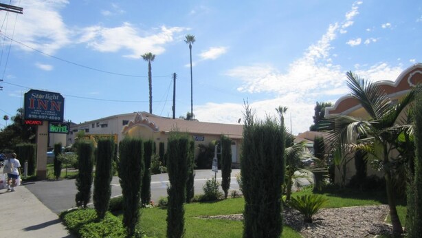 Un motel StarLight Inn con cielo despejado, palmeras y un césped bien cuidado.