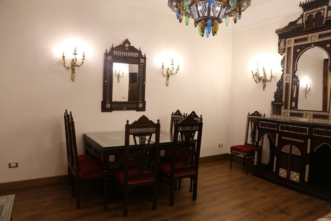 Una sala da pranzo con tavolo e sedie in legno, applique decorative e un grande specchio.