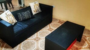 A black sofa with patterned cushions and a black ottoman on a hexagonal patterned floor. - La Casa (San Lorenzo)