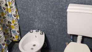 A bathroom with a bidet, a toilet, and a shower curtain with a floral pattern. - La Casa (San Lorenzo)
