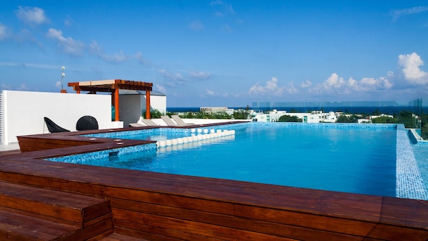 Ein Pool mit Überlauf und Blick auf die Stadtlandschaft, umgeben von einer Holzterrasse mit Sitzgelegenheiten.