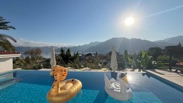 Een buitenzwembad, ligstoelen bij het zwembad