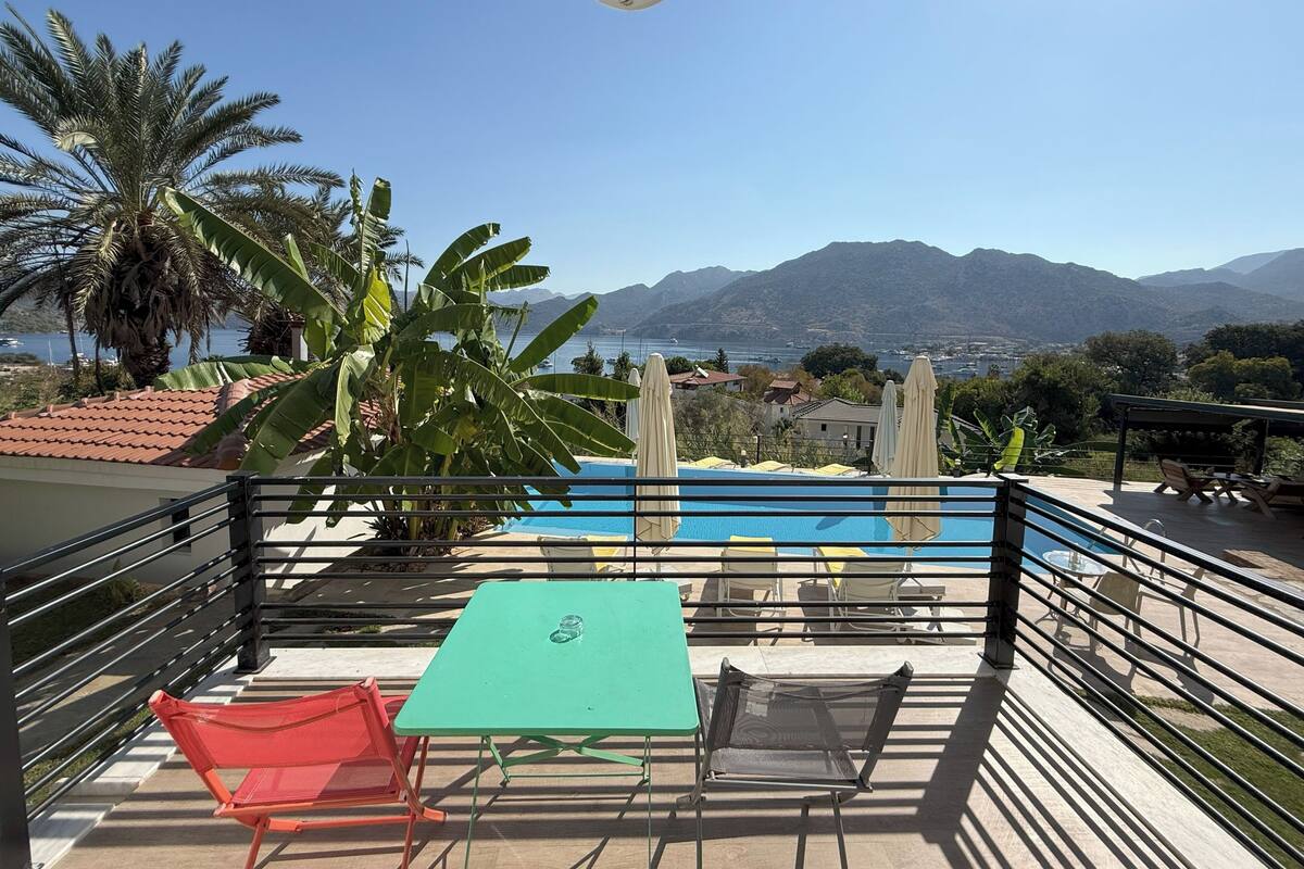 A balcony with a pool, chairs, and a table.