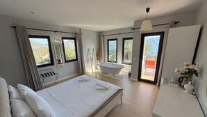 A modern bedroom with a large bed, a bathtub, and a balcony with a view. - Gala Selimiye (Marmaris)
